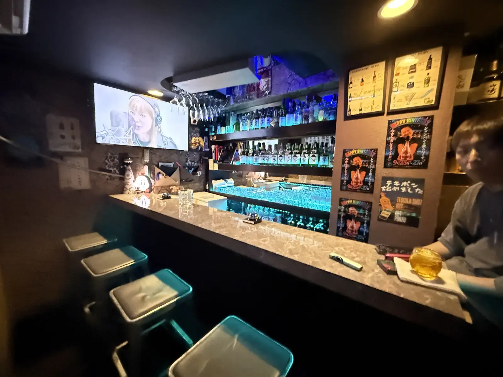 開店前のBAR NOMENOMEの店内。大理石調のカウンターと椅子、奥にカラオケの画面